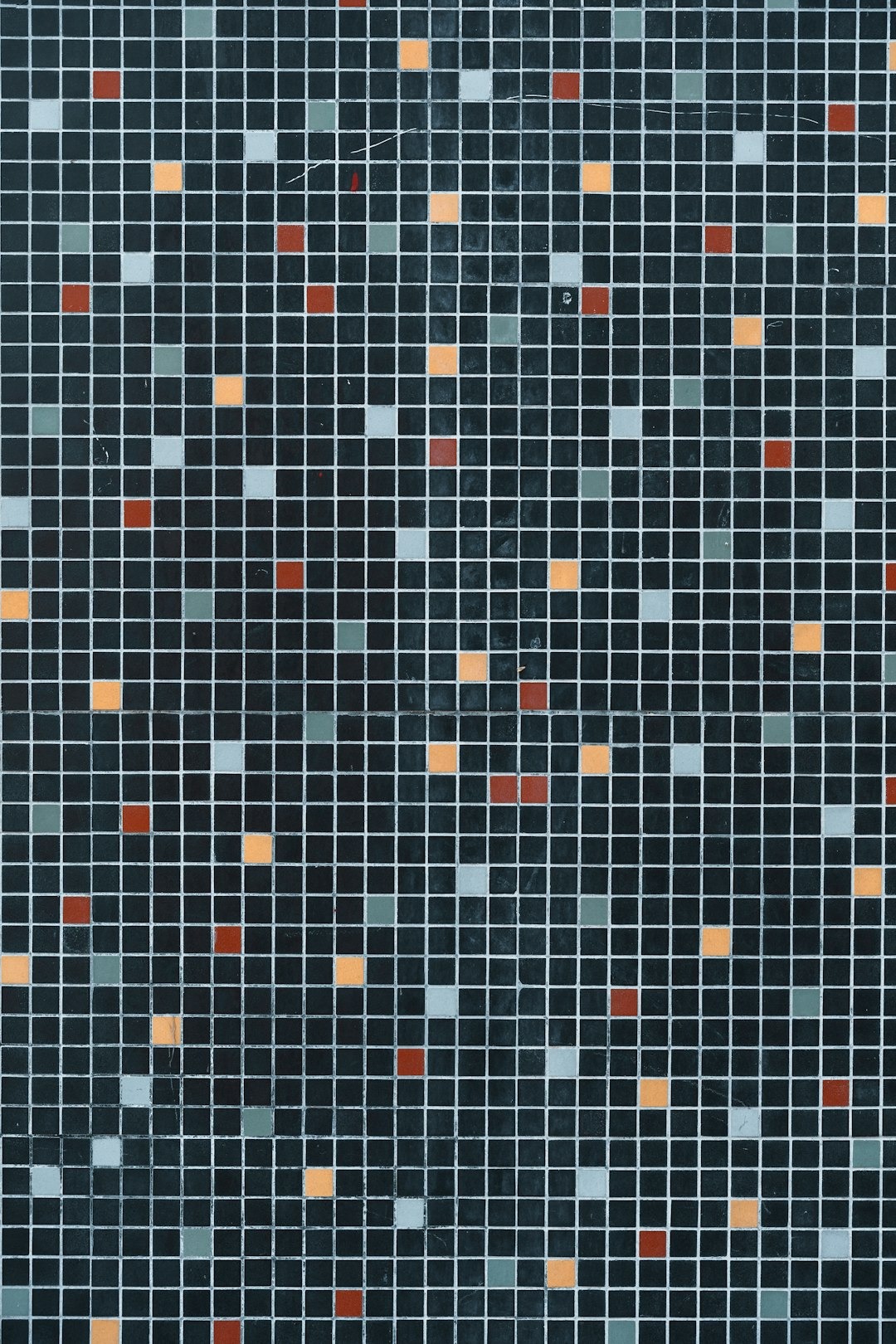 A mosaic surface featuring dark grey tiles with orange and blue accents.